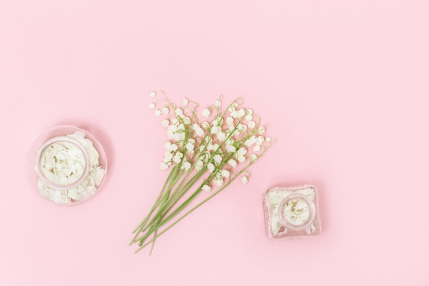 Pequeñas primeras flores de primavera lirios del valle y hermosa botella de vidrio con pétalos secos para aromaterapia.