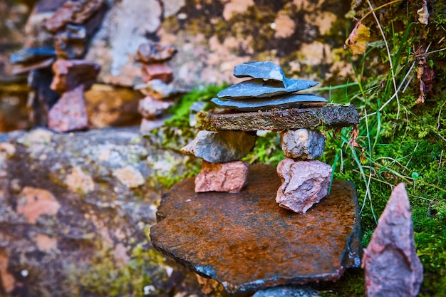 Pequenas rochas de pedra empilhadas em forma bonita contra rochas cobertas de líquen e musgo