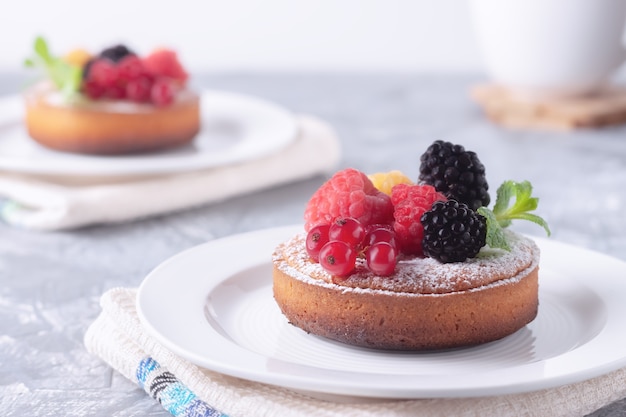 Pequeñas tartas de frutas caseras frescas con frambuesas, grosellas y moras en la mesa