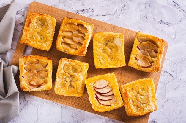 Foto pequeñas tartas de hojaldre al revés con manzana y plátano en la vista superior del tablero