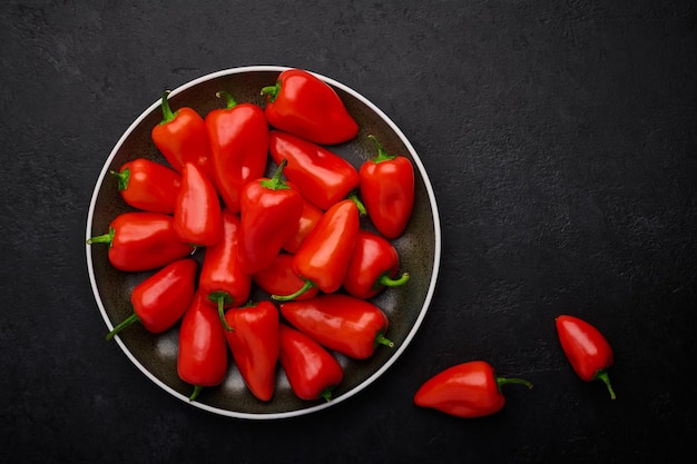 Pequeñas vainas de pimientos rojos en un plato de fondo de pizarra oscura