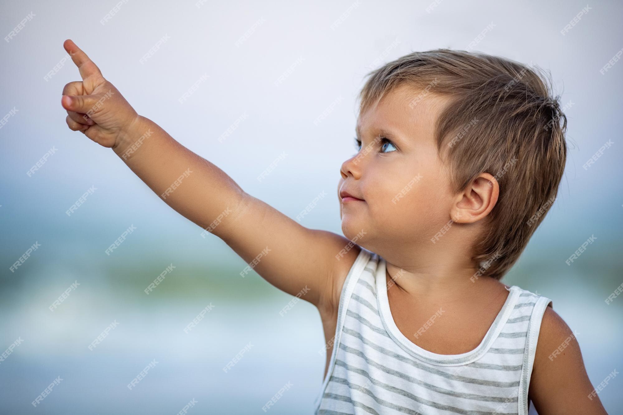 pequeño y adorable niño calvo bronceado con una camiseta de rayas blancas y negras con cabello dorado claro y grandes ojos azules se muestran a lo lejos en las