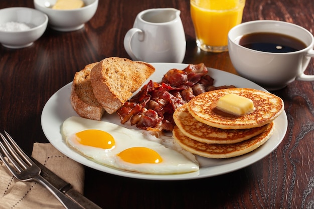 Foto pequeno-almoço americano tradicional com ovos, panquecas com bacon e torrada.