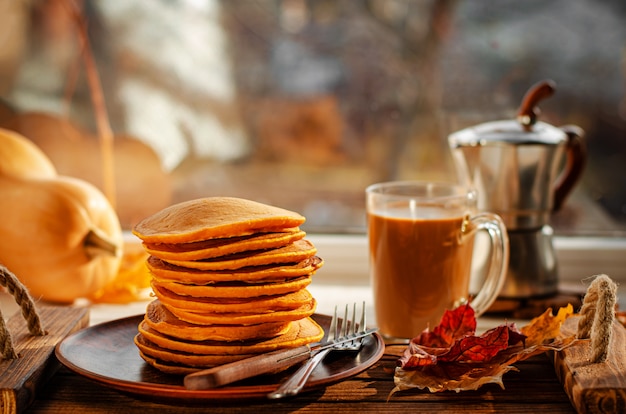 Pequeno-almoço americano tradicional de panquecas de abóbora e café na janela.