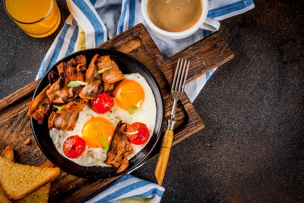 Pequeno-almoço inglês americano caseiro tradicional, ovos fritos, torradas, bacon, com caneca de café e suco de laranja