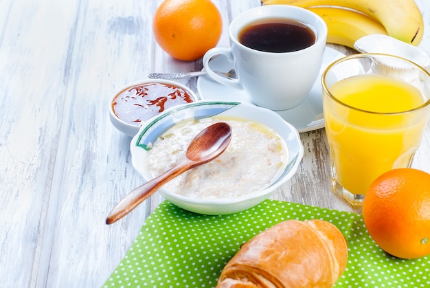 Pequeno-almoço saudável com aveia com manteiga, croissant e café