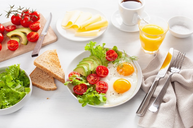 Pequeno-almoço saudável com ovos fritos, abacate, tomate, torradas e café