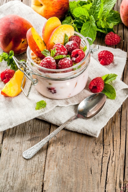 Pequeno-almoço saudável de verão. Durante a noite aveia em uma jarra, granola, nozes, framboesas frescas e pêssego