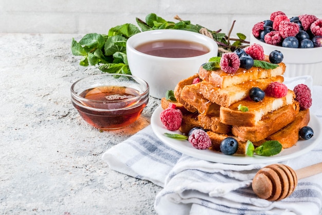 Pequeno-almoço saudável de verão, pão francês torrado assado com frutas frescas e mel, superfície de pedra cinza claro de manhã