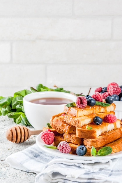 Pequeno-almoço saudável de verão, pão francês torrado assado com frutas frescas e mel, superfície de pedra cinza claro de manhã