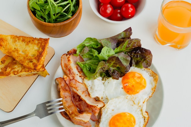 Foto pequeno-almoço saudável. ovos fritos, bacon, alface, tomate cereja e torradas. vista do topo