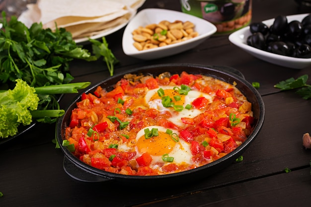 Foto pequeno-almoço turco - shakshuka, azeitonas, queijo e frutas.