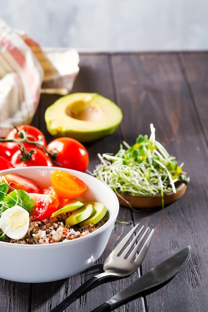 Pequeno-almoço vegetariano com quinoa, ovos, microgreen e legumes, chá verde com hortelã em uma mesa de madeira escura, plana leigos