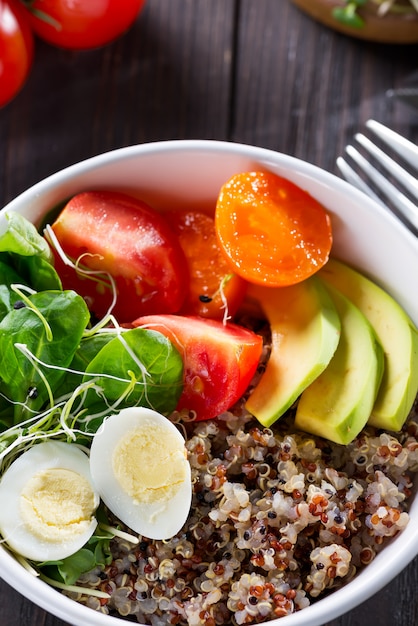 Pequeno-almoço vegetariano com quinoa, ovos, microgreen e legumes, chá verde com hortelã em uma mesa de madeira escura, plana leigos