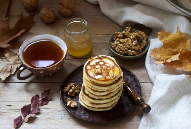 Pequeno-almoço vegetariano de bolinhos com mel, nozes e chá. outono ainda vida.