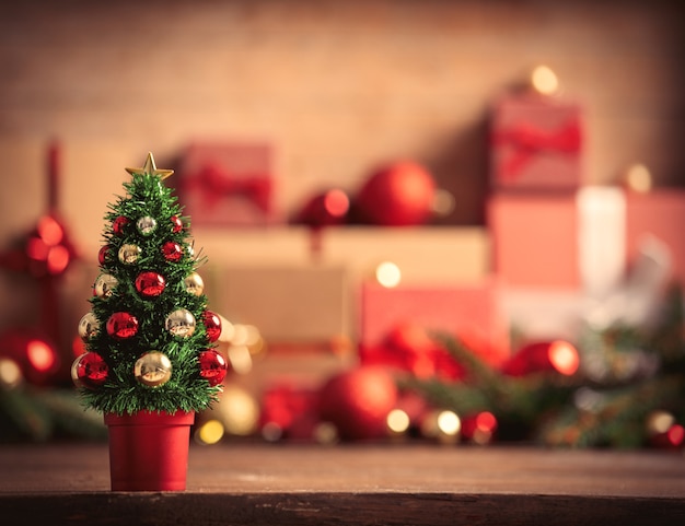 Pequeño árbol de Navidad y cajas de regalo en el fondo