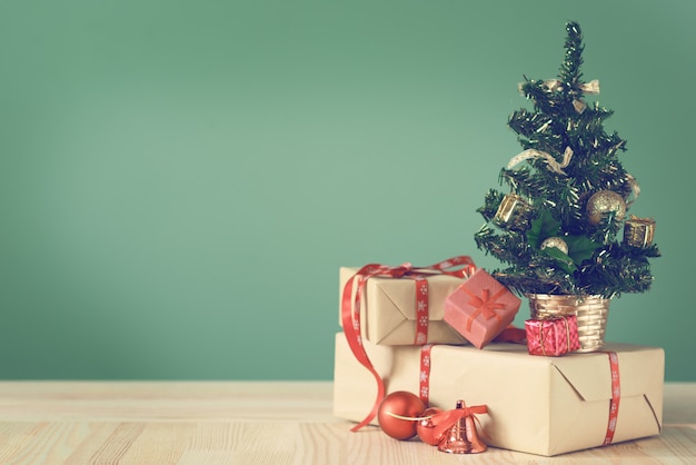 Pequeño árbol de Navidad y cajas con regalos en una mesa de madera.