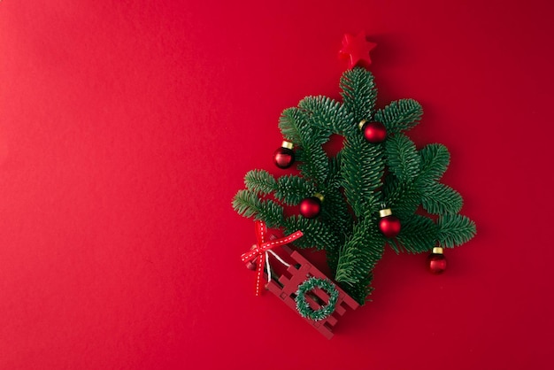 pequeño árbol de Navidad ensamblado a partir de ramas reales con decoración en un espacio de copia de fondo rojo