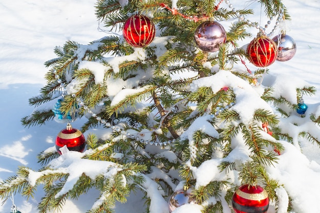 Pequeño árbol de Navidad festivo verde decorado con juguetes y abalorios en la nieve.