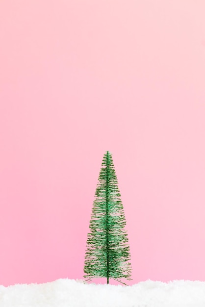Pequeño árbol de navidad sobre fondo rosa