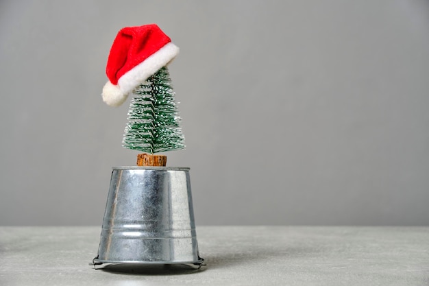 Pequeño árbol de Navidad con sombrero de Santa Claus está montado en un balde