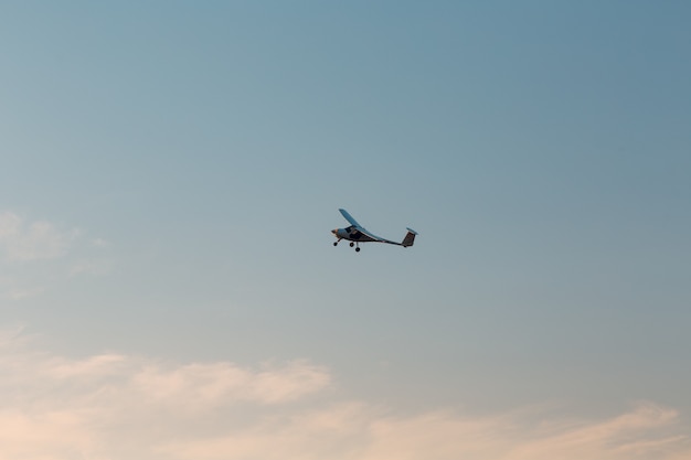 Pequeno avião monomotor voando contra o céu do pôr do sol