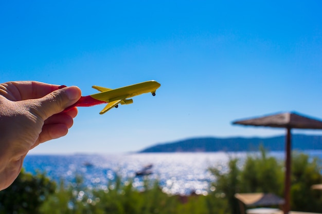 Pequeno avião na mão feminina no fundo do céu azul