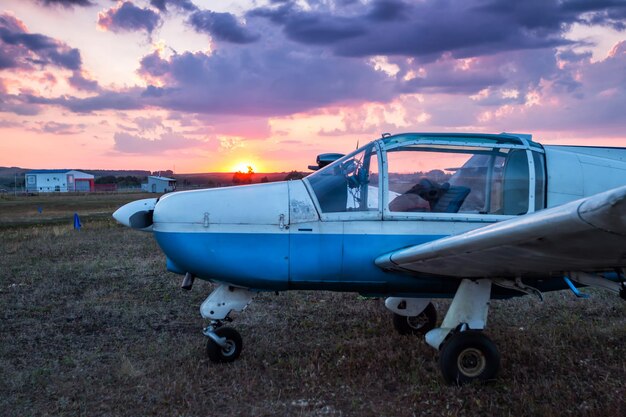 Pequeno avião privado estacionado no aeródromo ao pôr do sol cênico