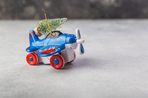 Pequeño avión con árbol de navidad en gris