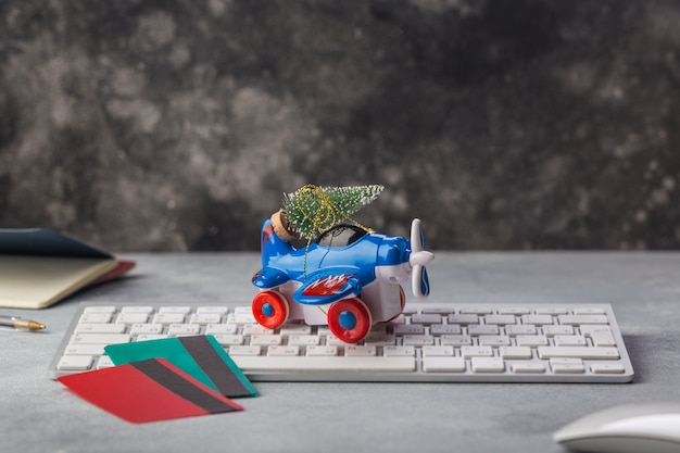 Foto pequeño avión con árbol de navidad, pasaportes, teclado, tarjeta de crédito de vacaciones