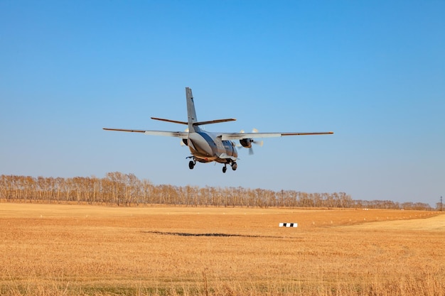 Un pequeño avión para el transporte de pasajeros y paracaidistas aterriza en un campo en una pista de aterrizaje con hierba bajo un cielo azul sobre los árboles en un día claro y sin nubes Patrulla aérea