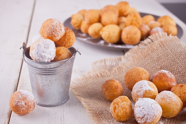 Pequeno balde e placa com pequenas bolas de donuts de queijo cottage caseiro recém-assados