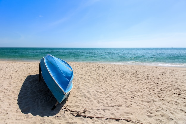 Pequeno barco à vela azul de cabeça para baixo coloca na praia