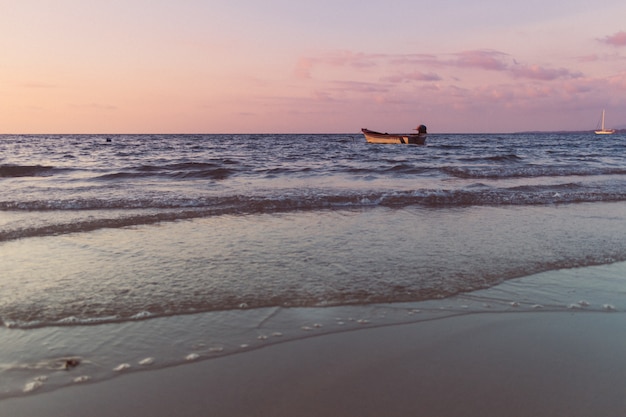 Pequeño barco aislado en el mar en el colorido concepto de puesta de sol de solitaria