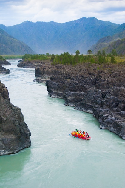 Foto pequeno barco de rafting em um rio rápido de montanha entre rochas