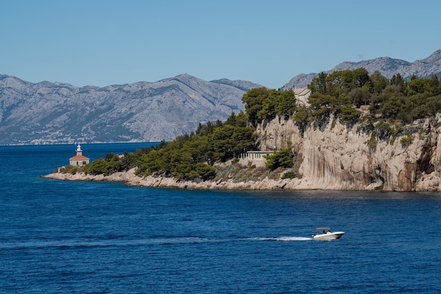 Un pequeño barco entra en un pintoresco puerto las montañas están cubiertas de vegetación el azul transparente