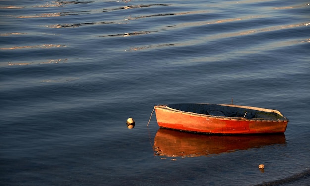 Foto pequeno barco laranja ancorado na costa