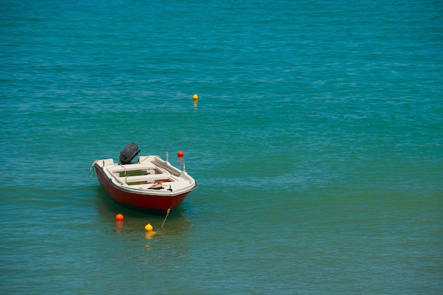 Pequeño barco de pesca en el mar en un día de verano Europa Colores de agua intactos El barco de belleza está atracado y se refleja en el agua de mar azul y verde en el soleado día de veranoCopiar espacio