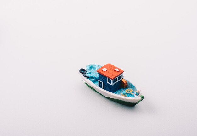 Foto pequeño barco de pesca modelo colorido colocado en blanco