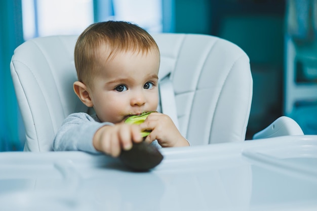 Foto pequeño bebé adorable comiendo aguacate vitamina y alimentos saludables para niños pequeños retrato de un hermoso niño de 8 meses