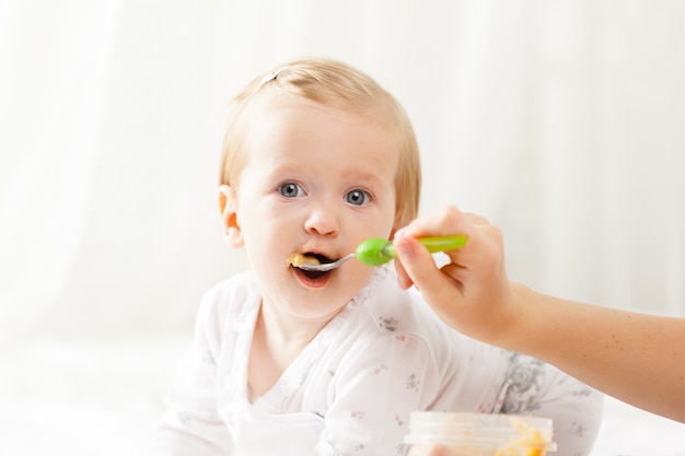 Pequeño bebé alimentándose con una cuchara