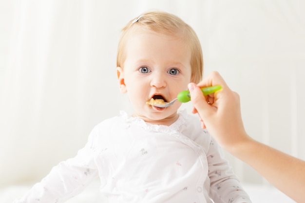 Pequeño bebé alimentándose con una cuchara