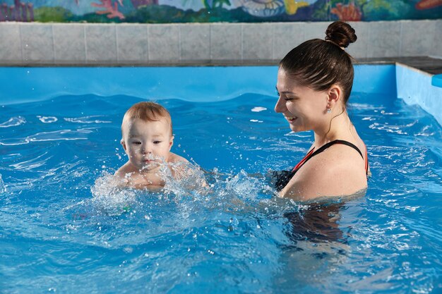 Pequeno bebê aprendendo a nadar na piscina com o professor