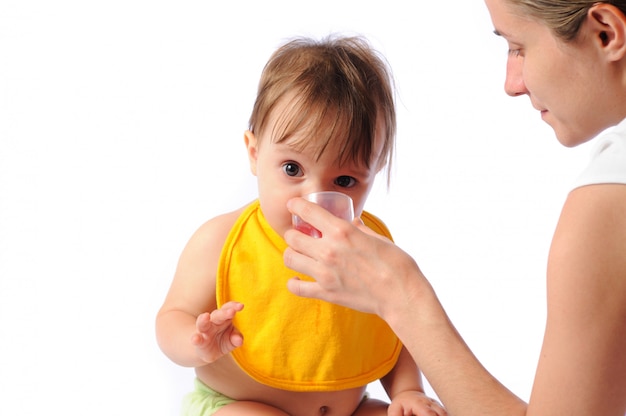 Pequeño bebé bebe agua de la taza