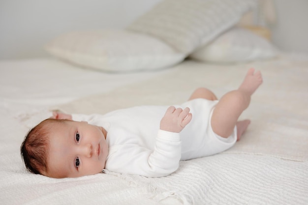 Pequeño bebé en la cama blanca