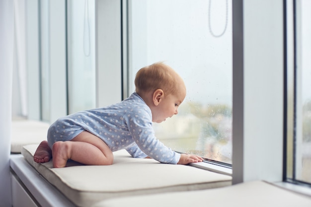 Pequeño bebé crawlibg cerca de la ventana grande