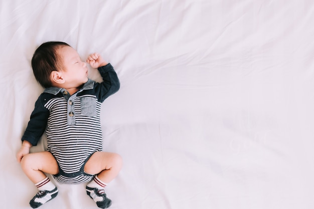 Pequeño bebé durmiendo en una cama blanca y suave en el dormitorio: momentos familiares felices