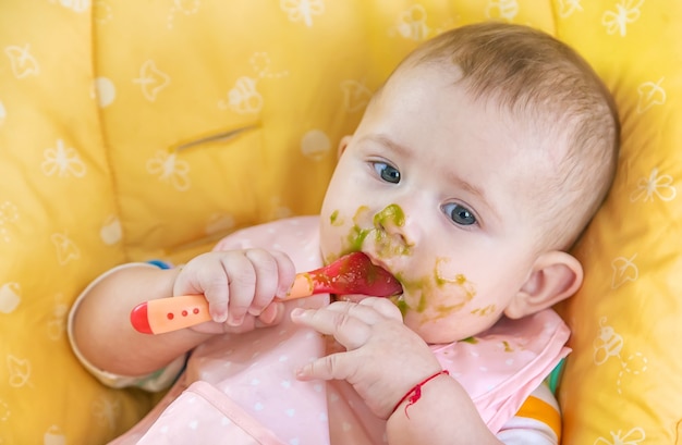 El pequeño bebé está comiendo puré de verduras de brócoli. Enfoque selectivo. Personas.