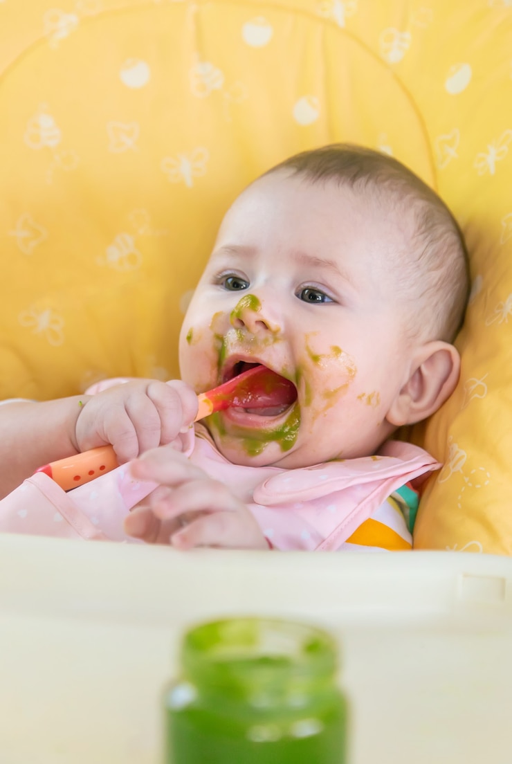 Foto el pequeño bebé está comiendo puré de verduras de brócoli. enfoque selectivo. personas.