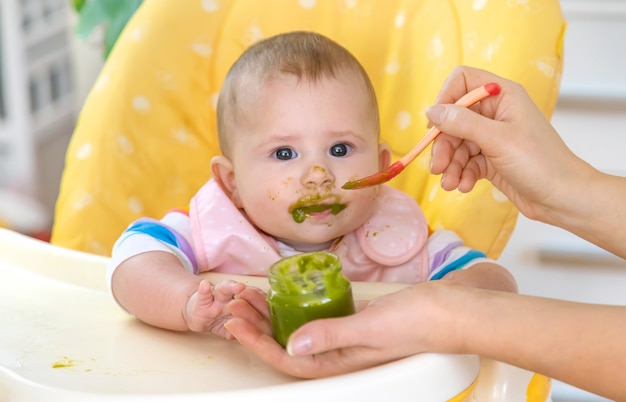 El pequeño bebé está comiendo puré de verduras de brócoli. Enfoque selectivo. Personas.